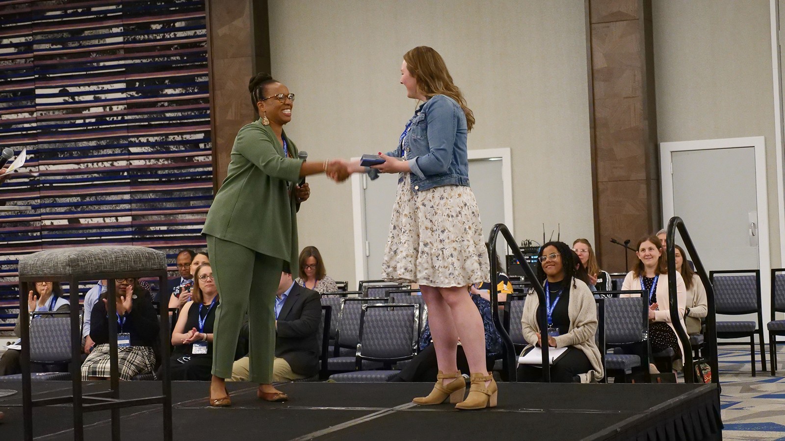 Two women shaking hands on stage while accepting award