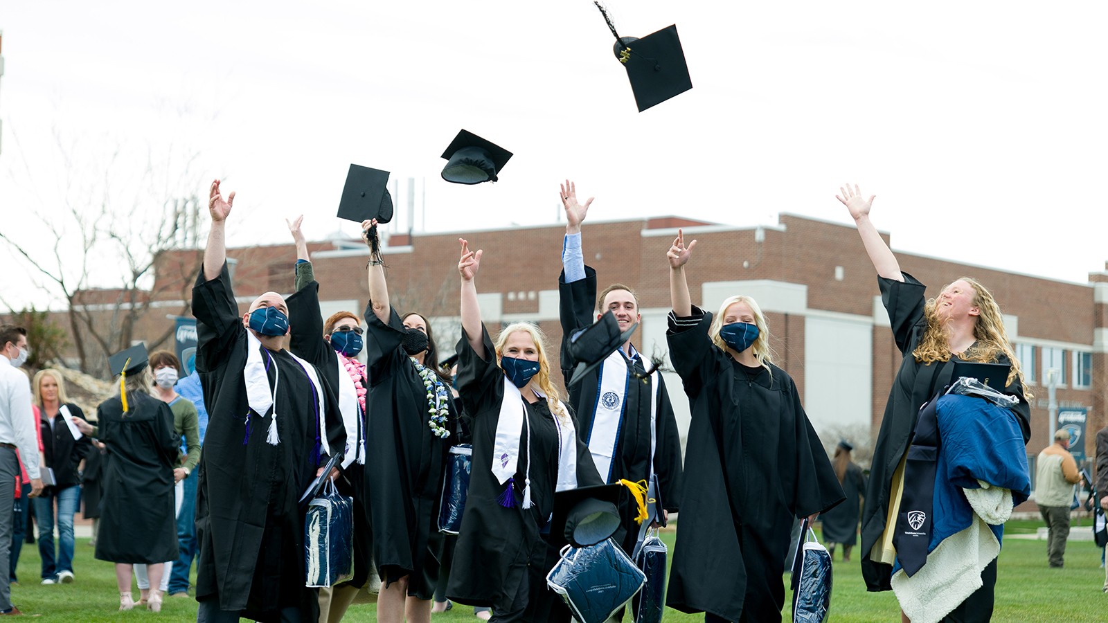 College graduages throw their hats into the air.