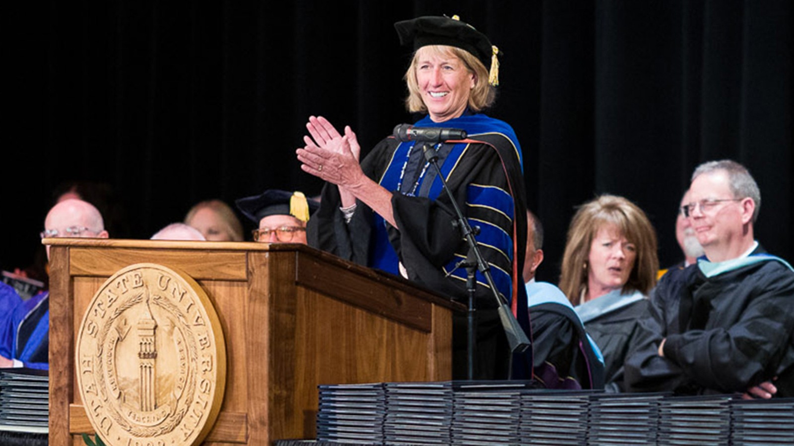 USU President Cockett stands at a podium conferring degrees
