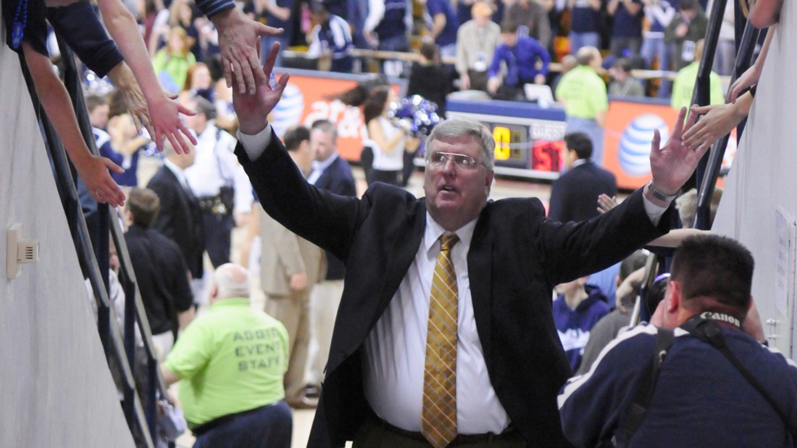 A basketball coach goes down the tunnel and gives high fives to fans