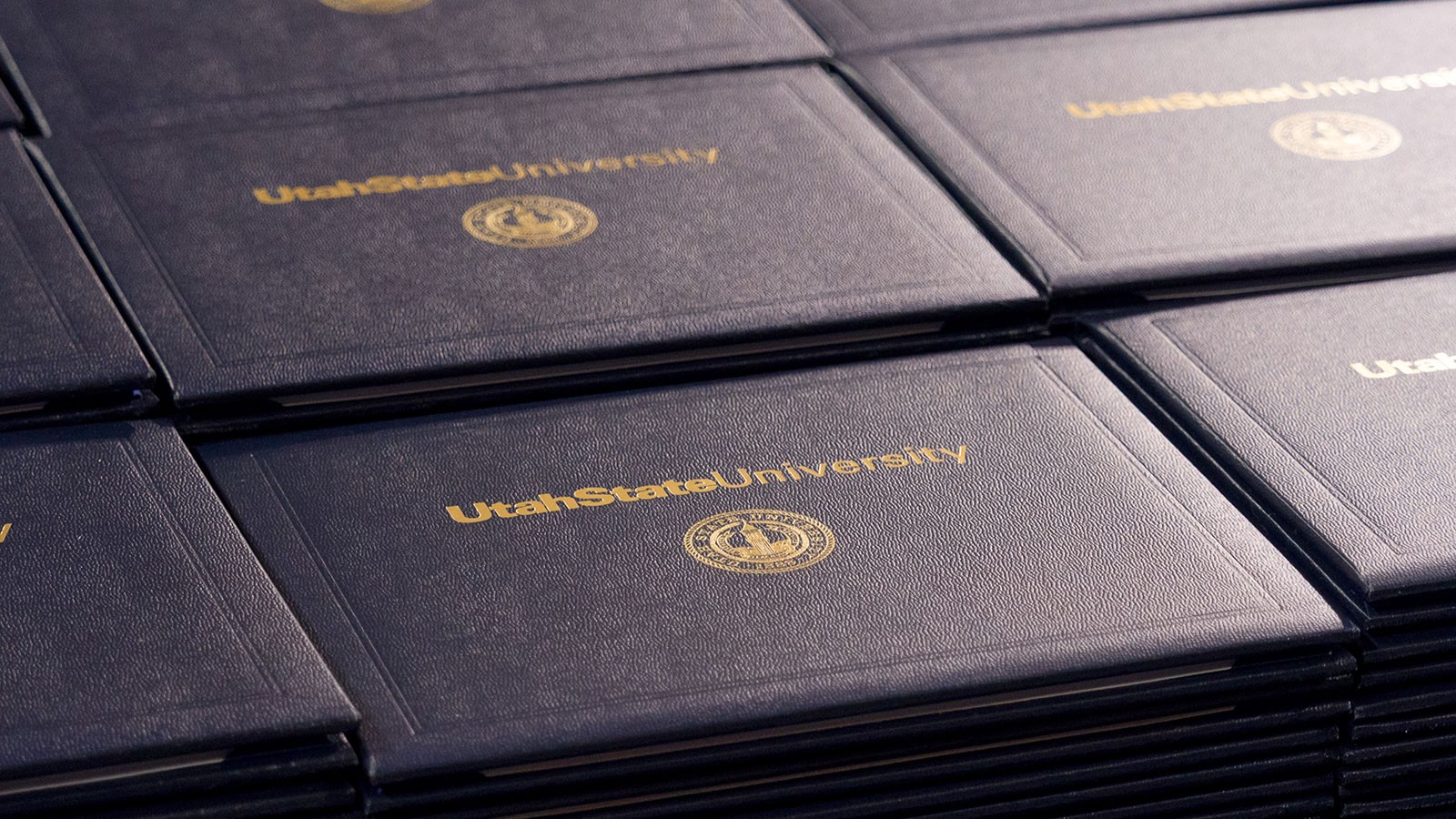 A set of stacked USU diploma covers.