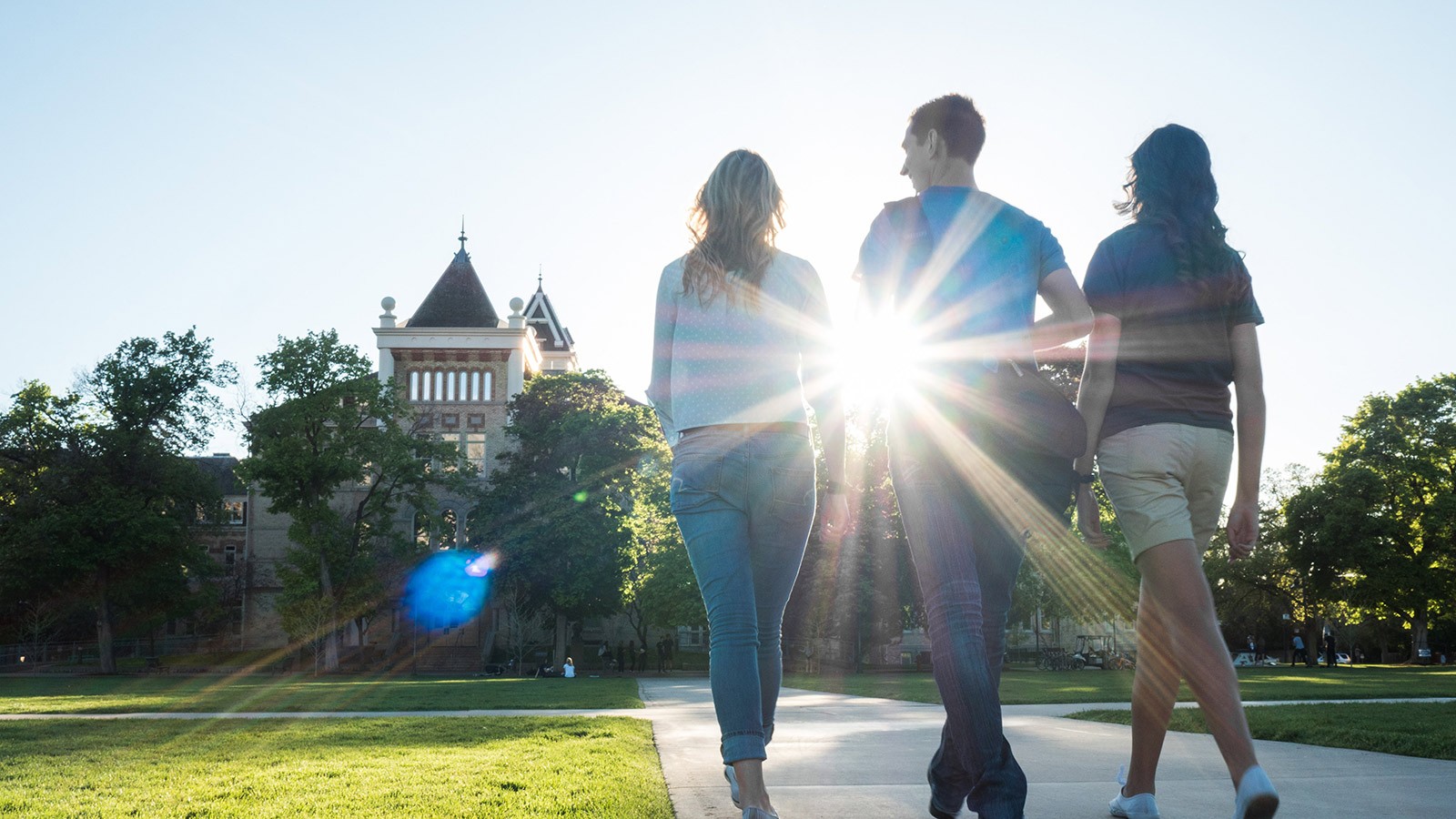 Three people walking on the Quad towards Old Main.