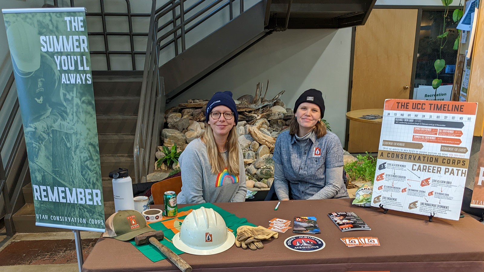 Two people sit at a Utah Conservation Corps table at a job fair.