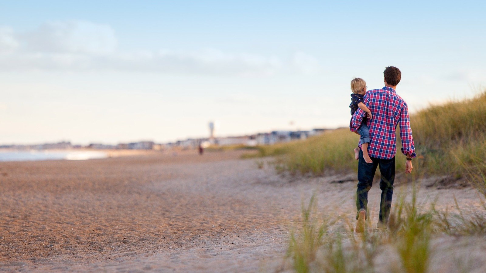 father and son walking on a beach.