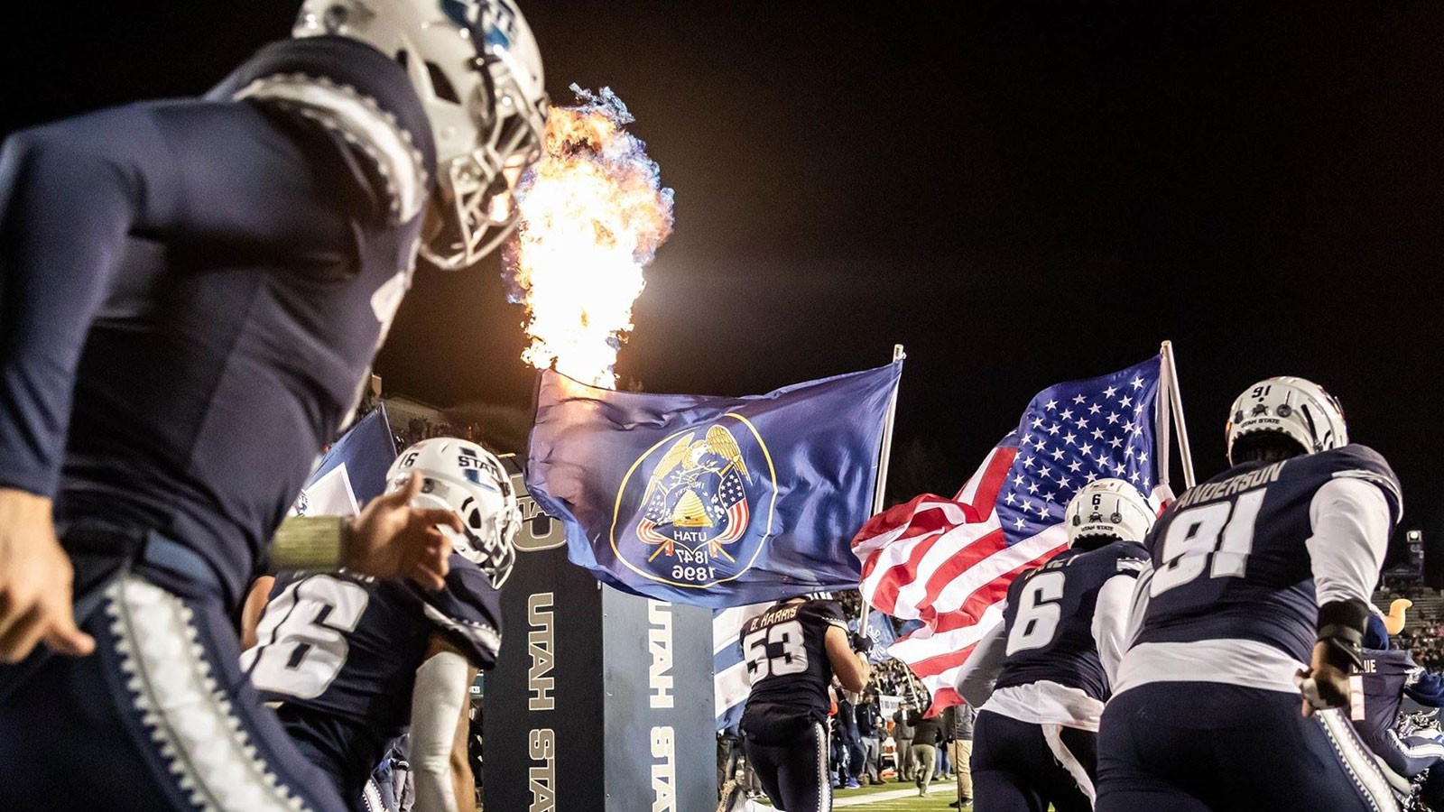 Football players run onto Maverik Stadium field.