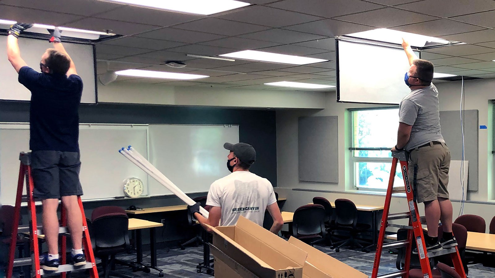USU facilities employees install lights in a classroom.