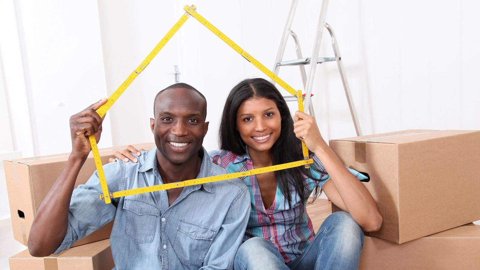 Couple holding a measuring tape in the shape of a house.