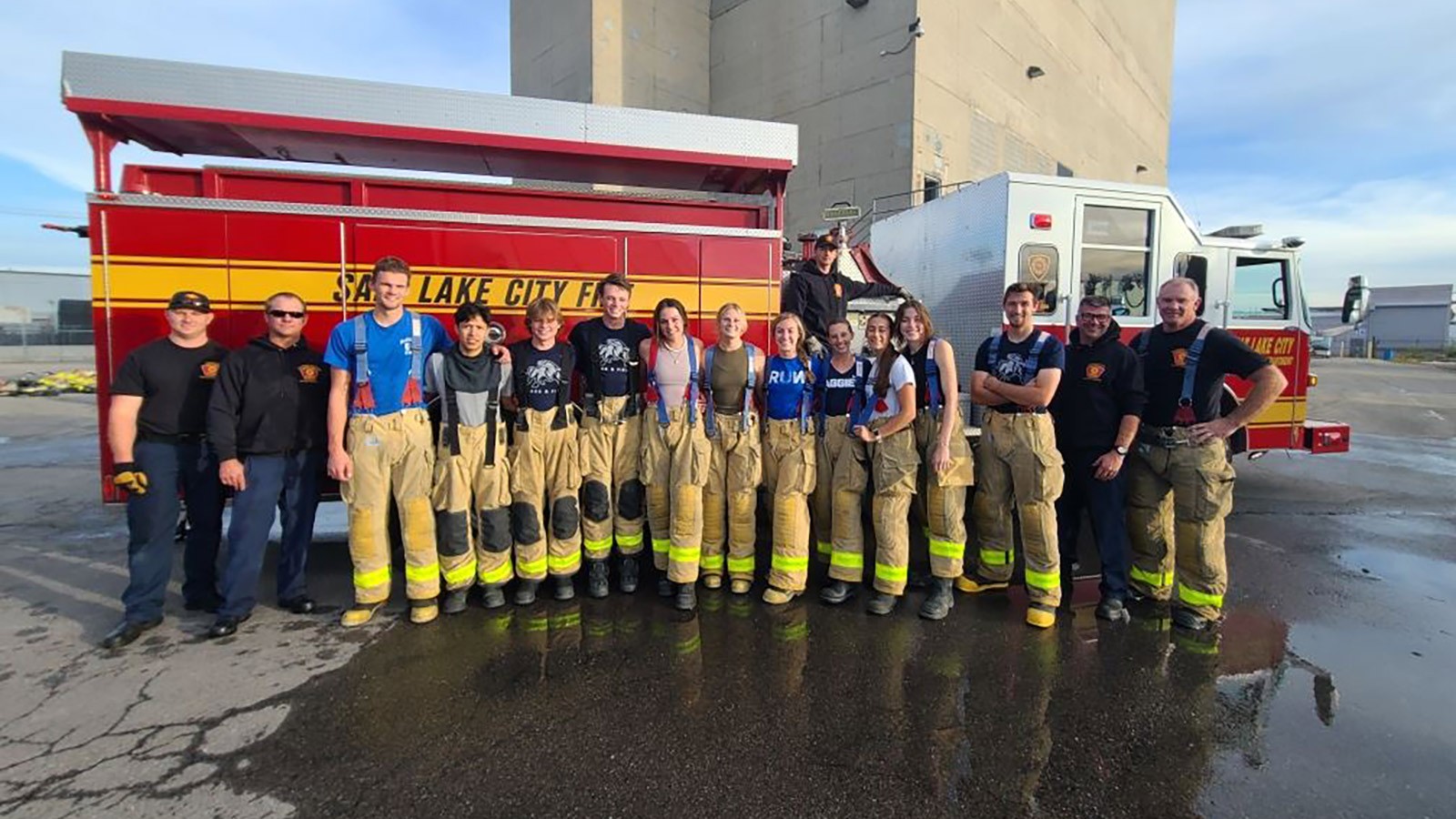 USU track and field sprinters and hurdlers gather for a photo in front of a fire truck.