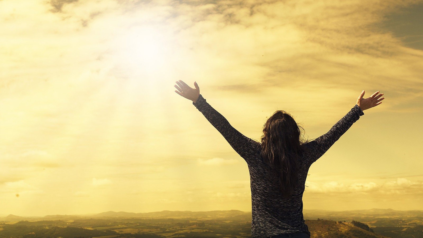 Person holding their hands up to a beautiful sunset.