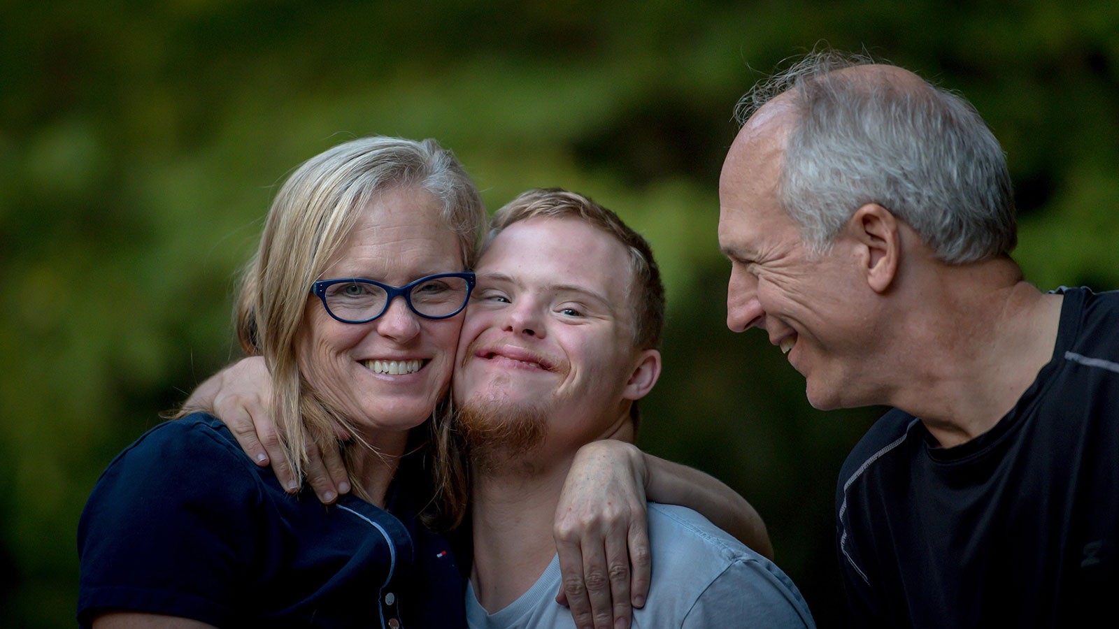 mother and father hugging a son with disabilities.