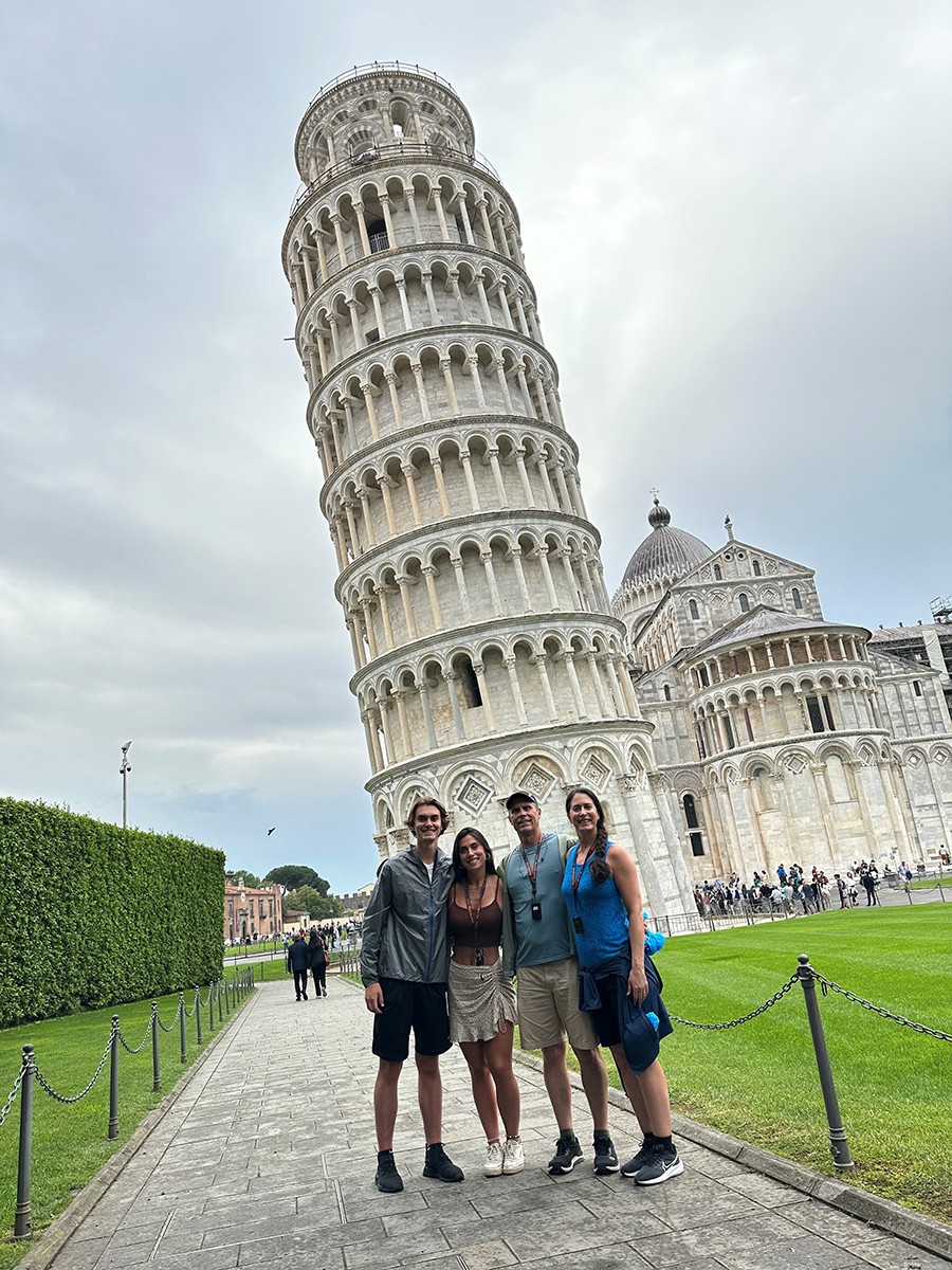 A family poses for a photo in front of the Leaning Tower of Pisa