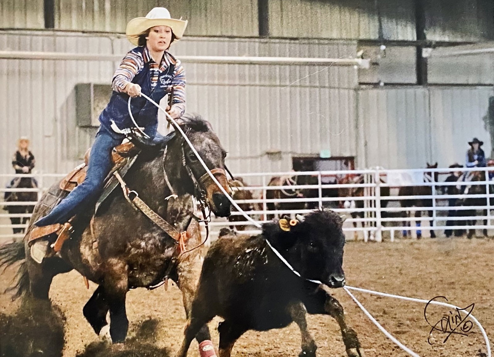 USU Rodeo Club member roping a cow in the arena.