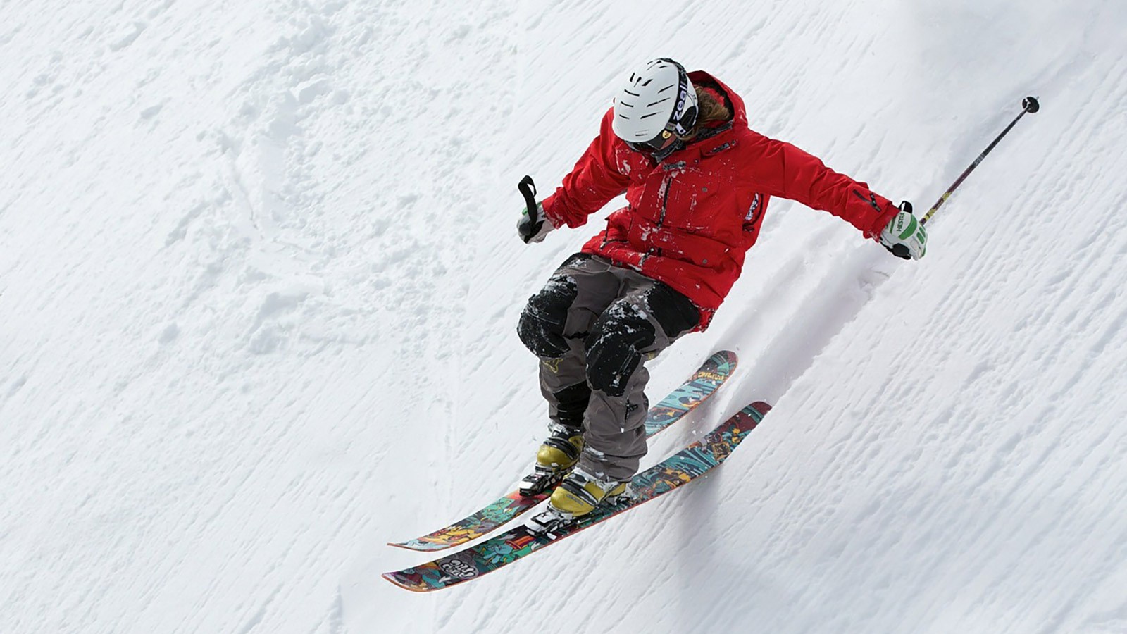 Skier skis down a ski slope.